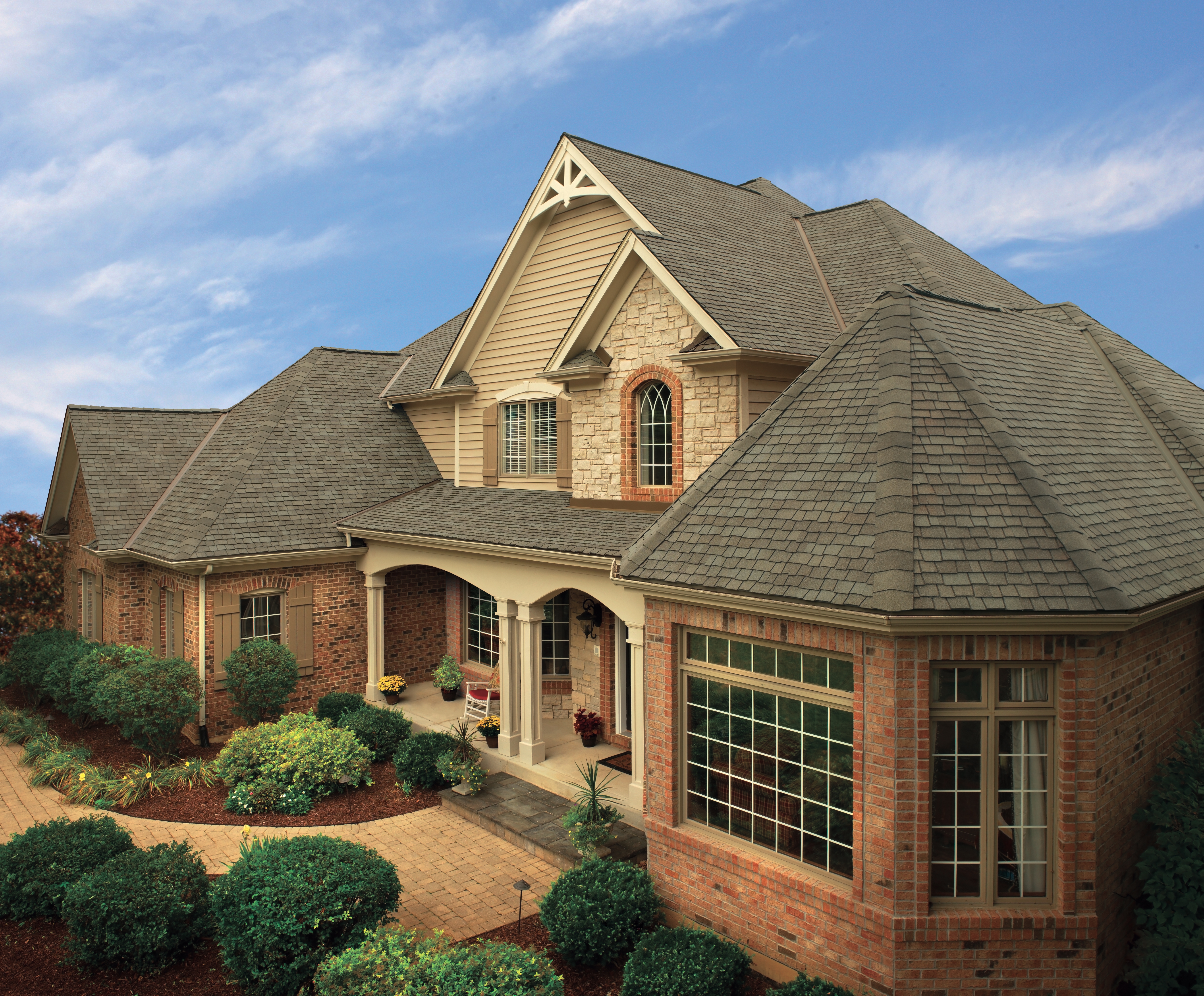 Dark gray roofing shingles against a light red brick exterior