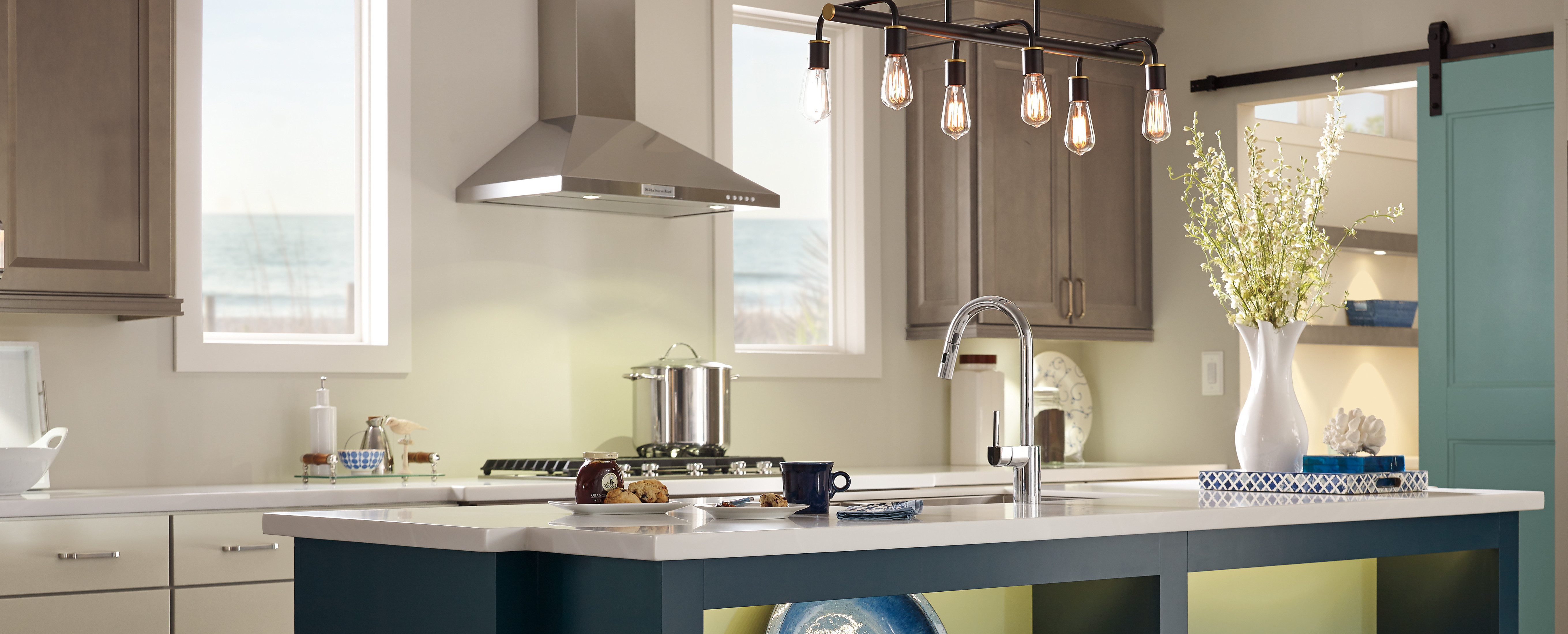 Elegant lighting fixtures with beige furniture and earth-tone dishes combine for this kitchen remodel