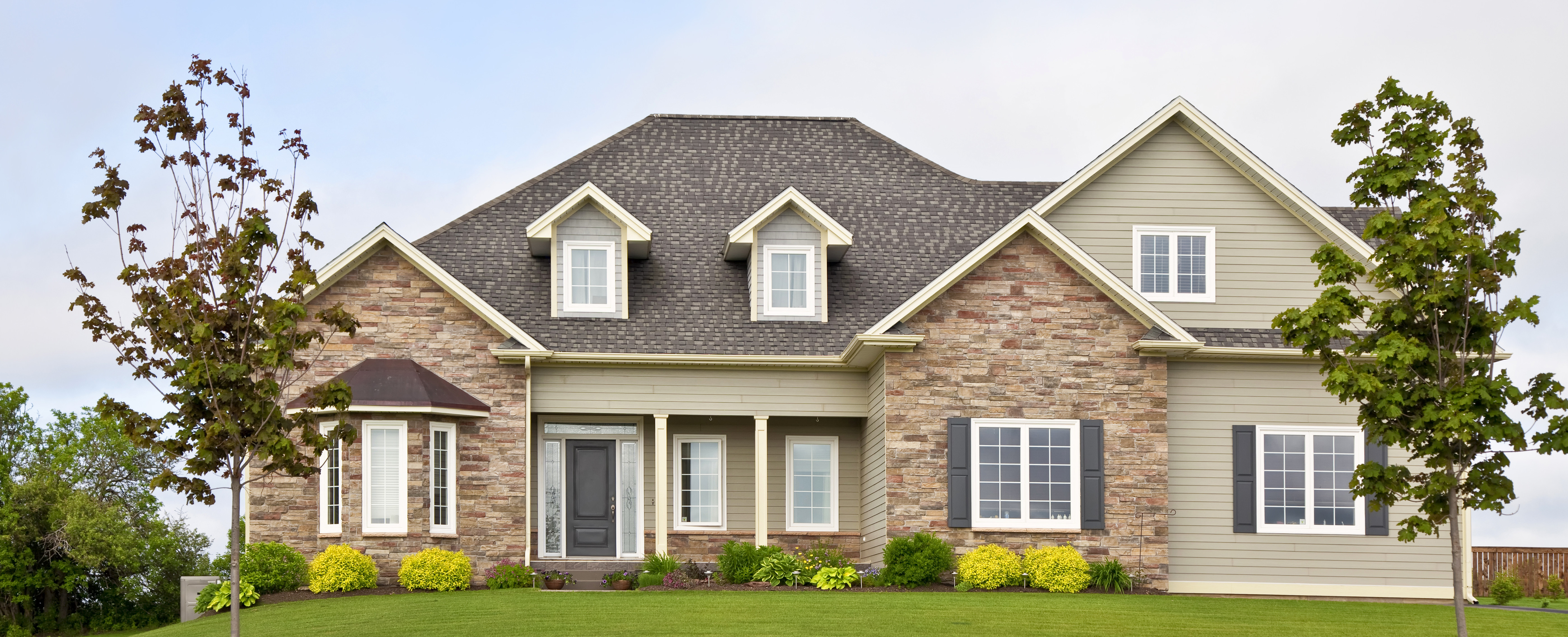 House with brick siding, white windows, and dark shingles